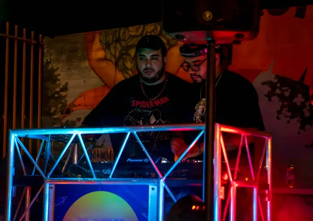 A DJ at the Electric Brew booth framed by blue and red stage lights