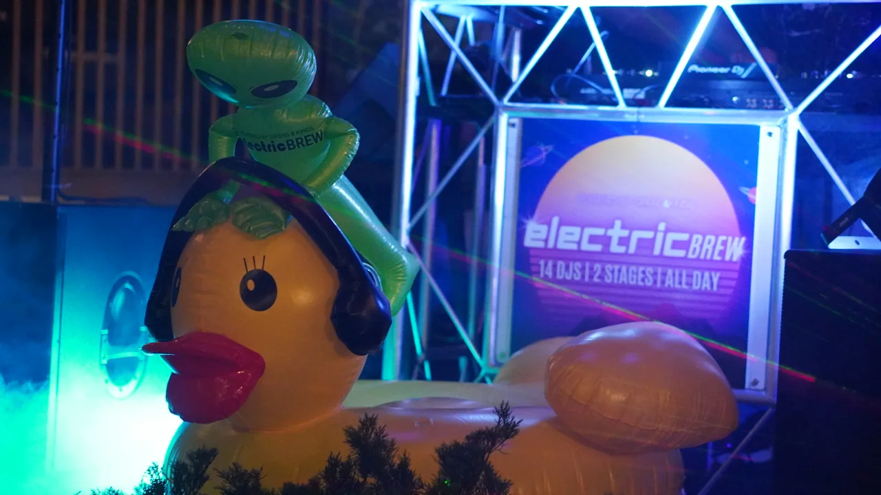 Inflatable aliens hanging out beside the illuminated Electric Brew DJ booth